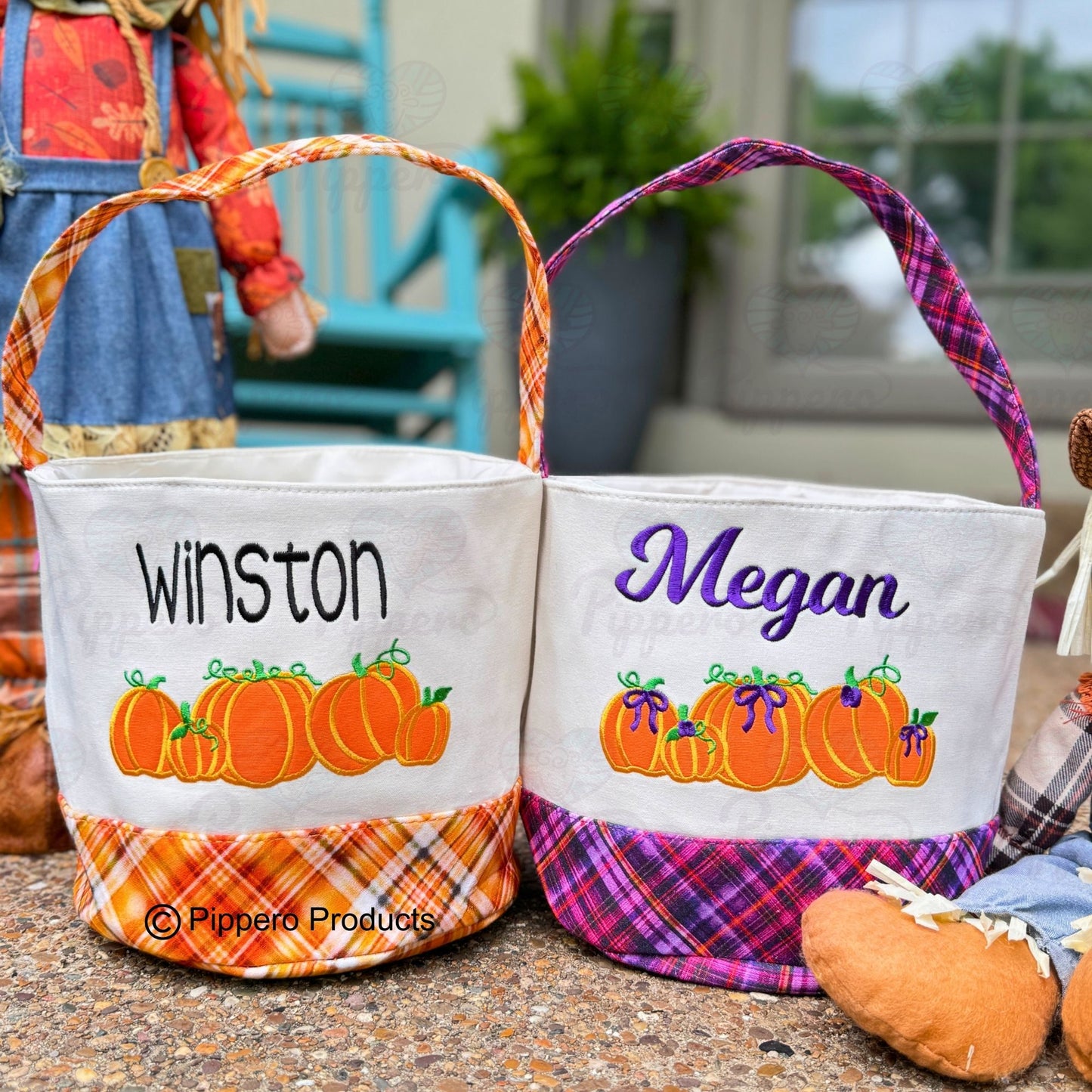2 Adorable Cavas Halloween baskets with plaid bottom and matching handle.  Design 5 Orange pumpkins with green stems.  One basket is orange plaid and one is purple plaid.  The purple plaid basket has purple bows on the pumpkins.  Baskets have embroidered names.  Winston is embroidered on the orange basket.  Megan is embroidered on the purple basket.  They are sitting on a front porch with Fall decorations behind them.
